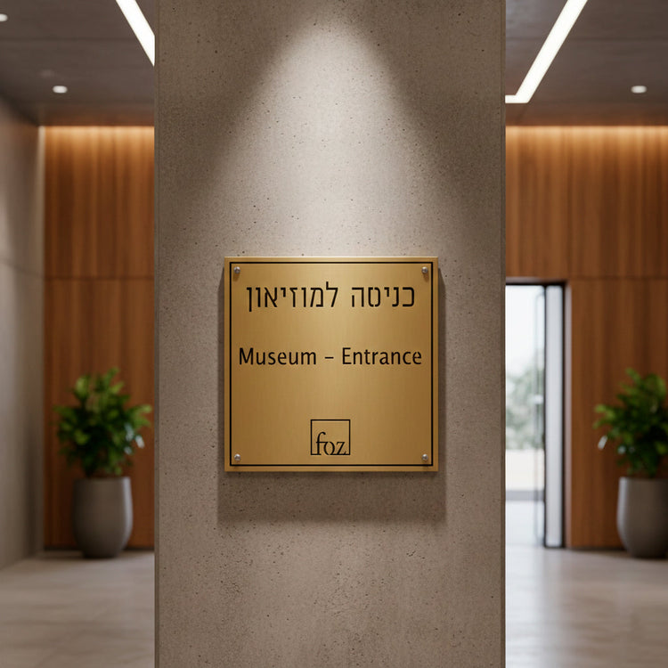 שלט פליז יוקרתי בגימור מוברש עם חריטה עמוקה לכניסה למוזיאון, מותקן על קיר בטון אדריכלי - סטודיו אספקלריה אספקלריה