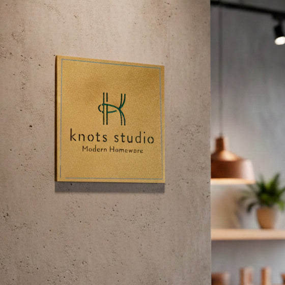 שלט פליז יוקרתי בחריטה עמוקה עם לוגו ירוק, מותקן על קיר בטון אדריכלי בגימור מוברש - סטודיו אספקלריה